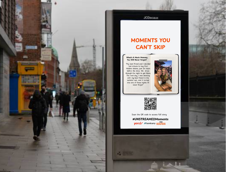People walking past Bandcamp, BBC Sounds and Yondr branded activation signage